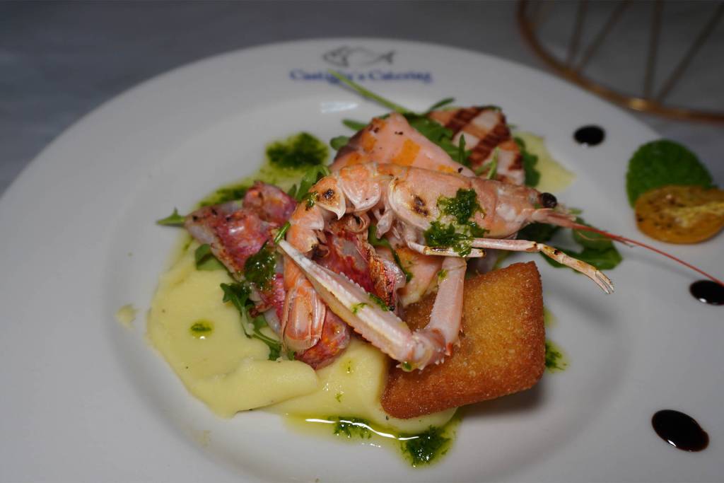 Trittico di pesce ( Spada, Salmone, Cipolla rossa) su crema di patate, crostino, olio al prezzemolo e scampo in bella vista